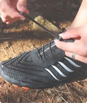 Grounded Footwear customer lacing up barefoot shoes on a hike